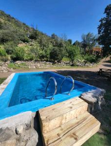 GuayacánArte Vitral Lodge - 4camas- aislada- terrazas -vista - piscina-sauna的一座带石墙和蓝色泳池景的游泳池
