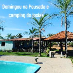 诺布里斯pousada camping do josias的一个带游泳池和棕榈树的度假村