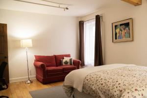 魁北克市皇家达尔豪斯酒店的一间卧室配有一张床和一张红色椅子