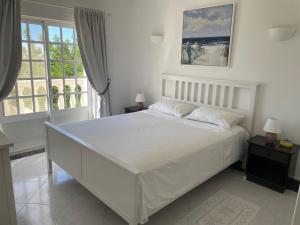 圣巴巴拉-迪内希Cabana do Monte的白色卧室设有大床和窗户