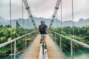 峰牙Phong Nha Dawn Home的骑着自行车穿过桥的人