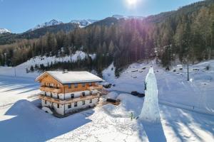 SchmirnNedererhof - Zimmer Alpenrose mit Gemeinschaftsküche的雪中建筑物的空中景观