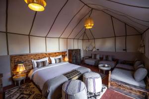 梅尔祖卡Golden Camp & Oasis的一间卧室配有一张床,一张沙发位于帐篷内