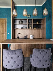 贝尔格莱德MOOW Apartments的厨房设有蓝色的墙壁和2个酒吧凳子