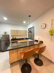 麦德林Apartamento cerca de todo en Medellín的厨房配有柜台和2把橙色椅子