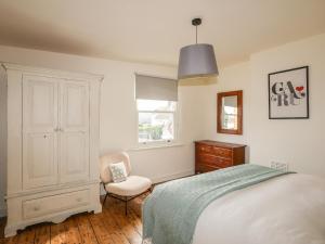 康威Shamrock Cottage的卧室配有床、椅子和窗户。