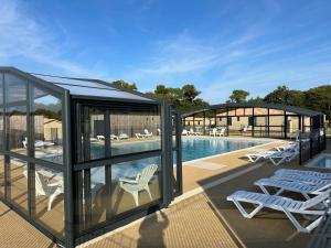 SaubriguesCottage parc résidentiel de loisir的一个带椅子的凉亭和一个游泳池