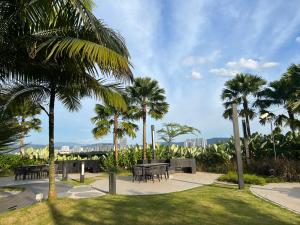 吉隆坡Eaton Residence KLCC BY Galaxy Suites的一座公园,公园内有桌子和棕榈树,后面有一座城市