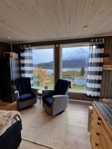 苏特兰Sjarmerende anneks i Sigerfjord, Vesterålen的客厅配有两把椅子和大窗户