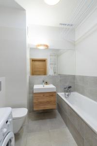 罗兹Przytulny apartament z parkingiem的一间带水槽、浴缸和卫生间的浴室