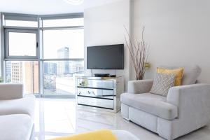 卡迪夫Luxury Cardiff City Centre Apartments的客厅配有电视、沙发和椅子
