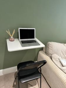 巴恩斯利Modern En-Suite Rooms Town Centre Self-Check In的一张坐在沙发旁的白色书桌上的笔记本电脑