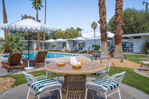 棕榈泉Monkey Tree Hotel by AvantStay Stylish Hotel in Palm Springs w Pool的池畔露台配有桌椅