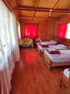 安东尼奥港Alma Patagona Hostel的带三张床和红色窗帘的房间