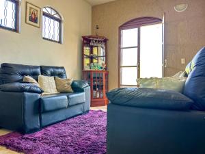 索罗卡巴Otima casa de campo com churrasq em Sorocaba SP的客厅配有2张蓝色皮革沙发和紫色地毯