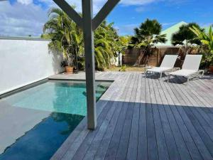 Saint MartinOrient Bay villa的一座房子旁的游泳池,配有木甲板和椅子