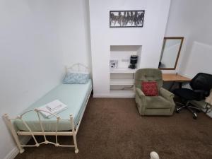 罗奇代尔Spacious Flat Near Rochdale Centre Self Check-in Free Parking & Fast Wi-Fi的一间卧室配有一张床、一把椅子和一张书桌