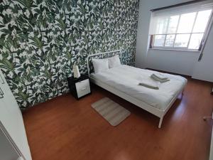 克卢什Sintra, T3 with terrace in Massama, Queluz, Sintra的小卧室配有一张带花卉壁纸的床