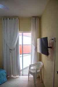 伊塔波阿Casa do Farol的客房设有电视、椅子和窗户。