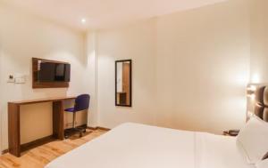 孟买Hotel Deluxe Residency的酒店客房设有一张床、一张书桌和一台电视机。