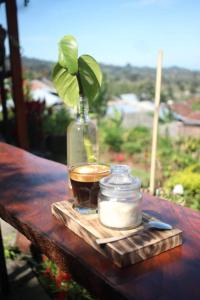 SapitBalelangga Bed & Breakfast的茶杯和木桌上的玻璃瓶