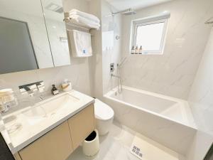 上海ZHome-Modern 3 bedrooms apartment - near NanJing Road的白色的浴室设有水槽、浴缸和卫生间。