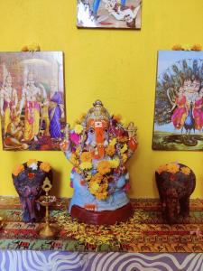 黎明之村WoodPacker Hostel Auroville Pondicherry的神像坐在桌子上,两瓶花