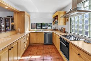 帕帕莫阿Poolside Serenity - Papamoa Beach Holiday Home的厨房配有木制橱柜和炉灶烤箱。