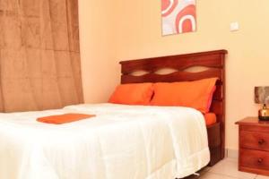 雅温得Appartement meublé, 2 douches, 2 chambres的卧室配有带橙色枕头的大型白色床