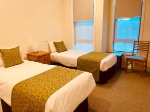 墨尔本Mary MacKillop Heritage Centre的酒店客房带两张床、椅子和窗户