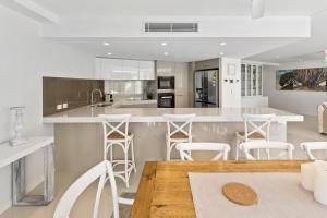 黄金海岸彩虹湾花环公寓的厨房配有木桌和白色凳子