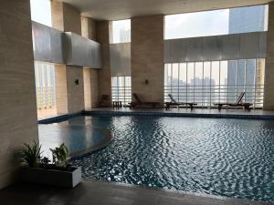 雅加达The H Tower Residence by YLS Stay的一座大型游泳池,位于一座带窗户的建筑内