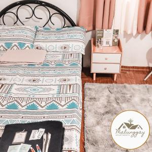 马里韦莱斯Malunggay Apartments的一间卧室配有一张床和一张桌子及床头柜
