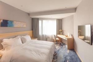 上海上海城市酒店的一间酒店客房,配有一张白色的床和一张书桌