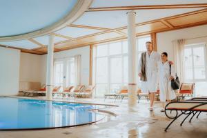 EmsingHotel Dirsch Wellness & Spa Resort的站在游泳池旁的男人和女人