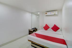 孟买OYO Hotel Blue Light Near Gateway Of India Mumbai的小卧室配有红色枕头的床