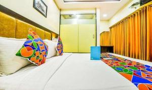 孟买FabHotel Ascot International II的一间卧室配有一张带色彩缤纷枕头的大床