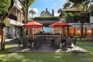 塞米亚克阿玛迪假日别墅酒店的庭院设有带椅子和遮阳伞的酒吧