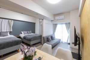 大阪Ocean Tsutenkaku的一间卧室配有两张床、一张沙发和一张桌子