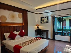高兰Lanta Riviera Resort - SHA Extra Plus的一间卧室配有一张带红色枕头的床和一扇窗户