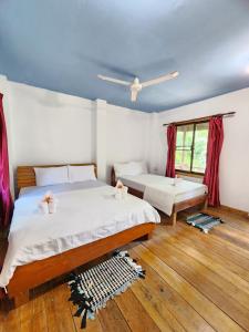 瓜隆岛Sweet Jungle Bungalows的一间卧室设有两张床,窗户配有红色窗帘