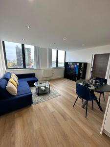 曼彻斯特1 Bed Apartment near Old Trafford with free car park的客厅配有蓝色的沙发和桌子