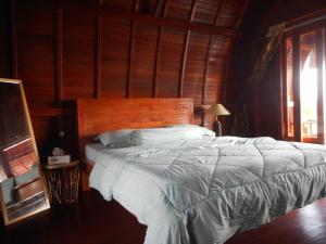BesakihCandra Homestay Besakih的一间卧室配有一张大床和木制床头板