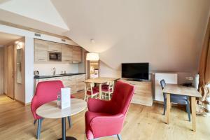 扎科帕内Radisson Blu Hotel & Residences的一间厨房和一间带红色椅子及桌子的客厅