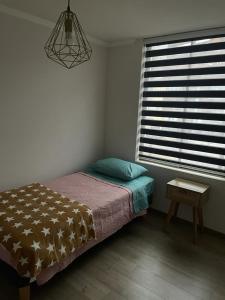 伊基克Hermoso departamento的一间卧室配有一张床、一张桌子和一个窗户。