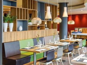 柏林柏林米特诺沃特酒店的餐厅配有桌椅和吊灯