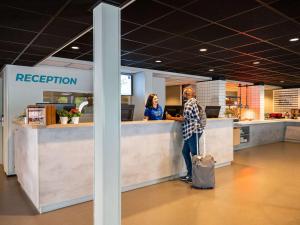 巴德胡弗多普阿姆斯特丹机场宜必思快捷酒店的办公室接待台站立的人