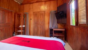 金巴兰RedDoorz at Villa Krisna Balangan Beach的一间卧室配有一张带红色毯子的床和一台电视。