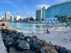 圣胡安Condado Beachfront Tantra Apartment的一片海滩,人们在水中和建筑中