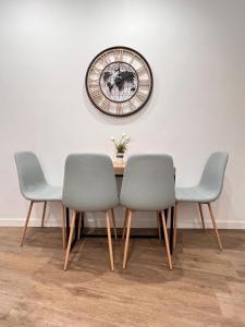 那不勒斯Serra Di Cassano Apartment的餐桌、三把椅子和墙上的时钟